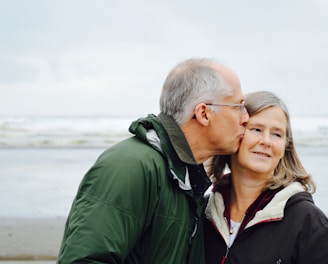 man kissing woman on check beside body of water