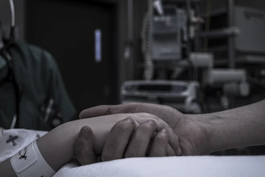 A caring nurse gently assisting a patient with post-operative exercises in a bright recovery room.