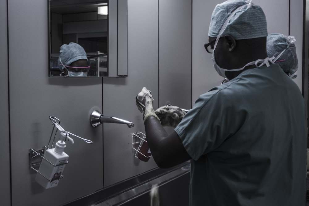 man wearing surgical suit near mirror