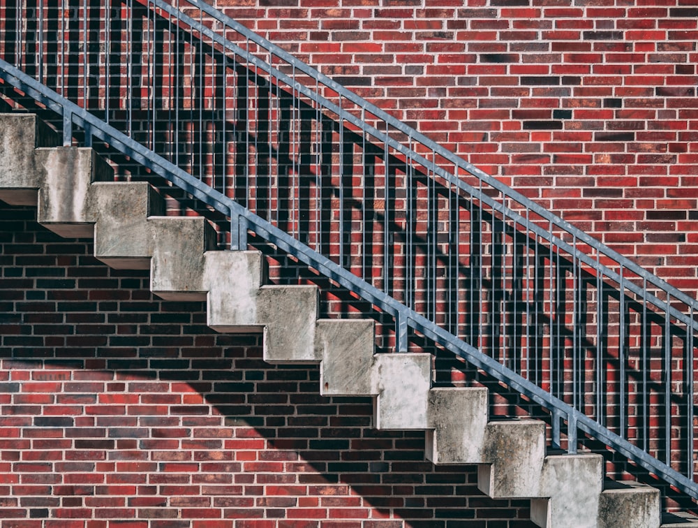 Escalera de metal gris junto a la pared de ladrillo rojo