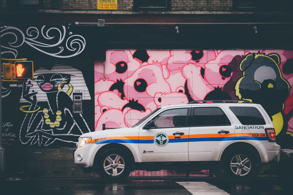 estacionamento SUV branco perto do muro de grafite