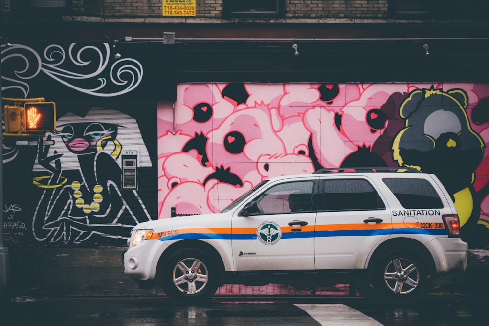 weißer SUV-Parkplatz in der Nähe einer Graffiti-Wand