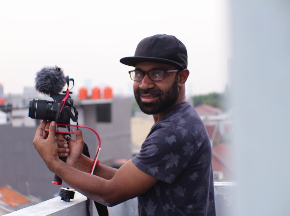 uomo che tiene la macchina fotografica accanto alla ringhiera della terrazza