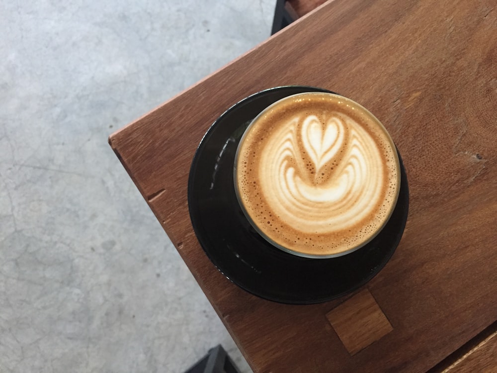 black ceramic coffee cup and saucer on brown wooden surface