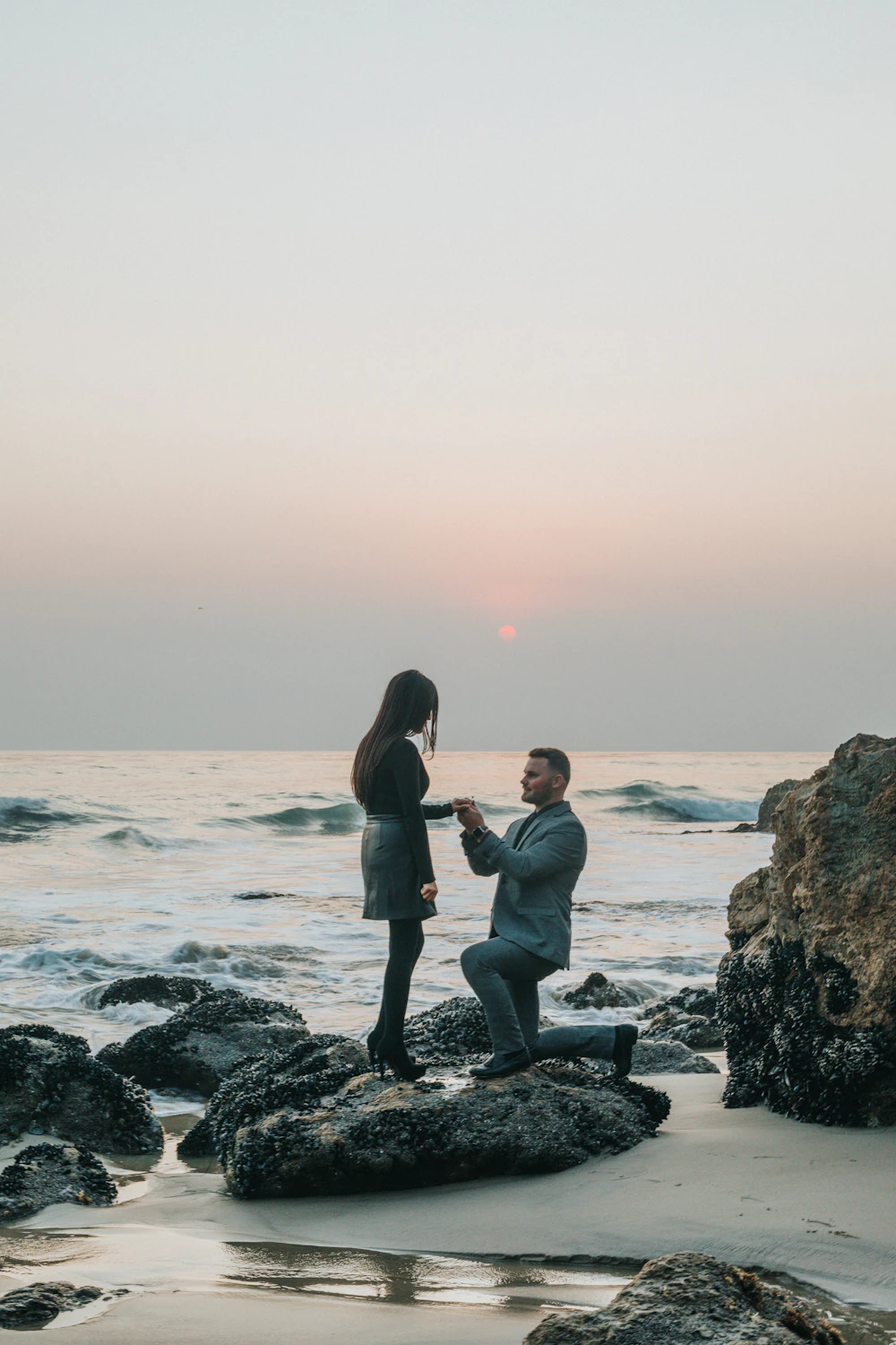 Man kneeling to propose to his partner on the beach
