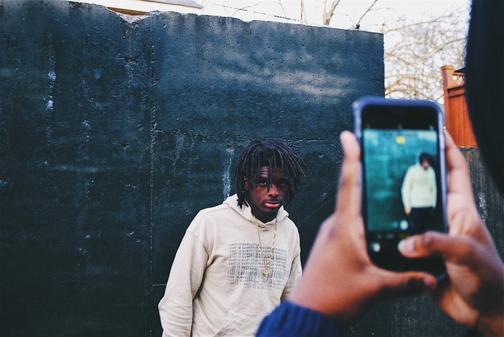 person taking picture of man wearing white pullover hoodie