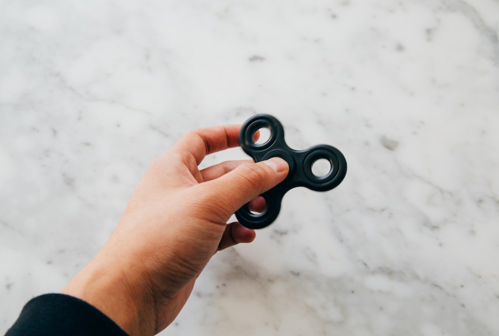 person using black fidget spinner