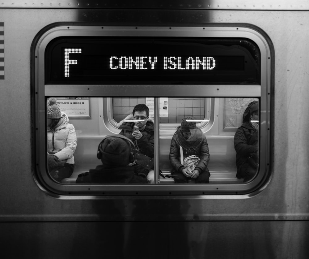 grayscale photo of persons sitting on train