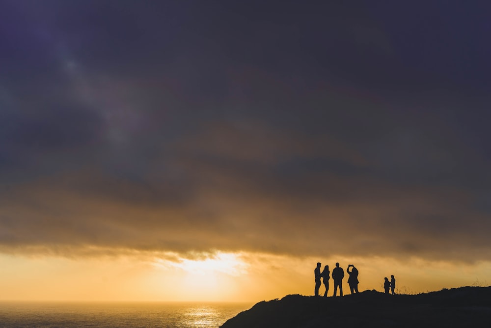 Seis pessoas em pé no penhasco da montanha na hora dourada