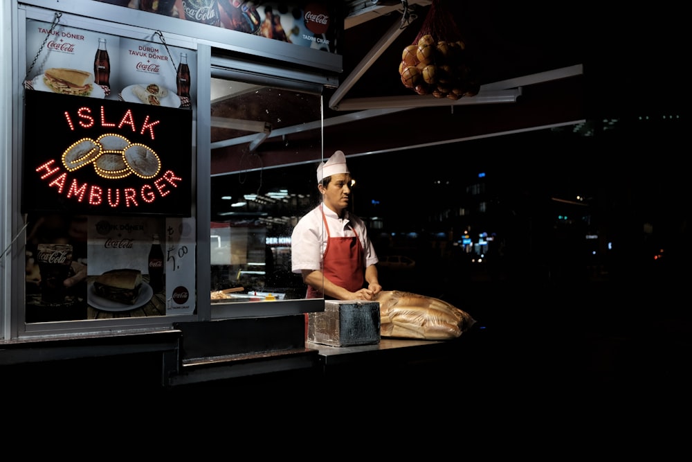 man standing on hamburger stall during night time