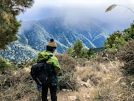 A model wearing a hemp jacket and trousers standing on a trail with the Himalayas fading into mist behind.