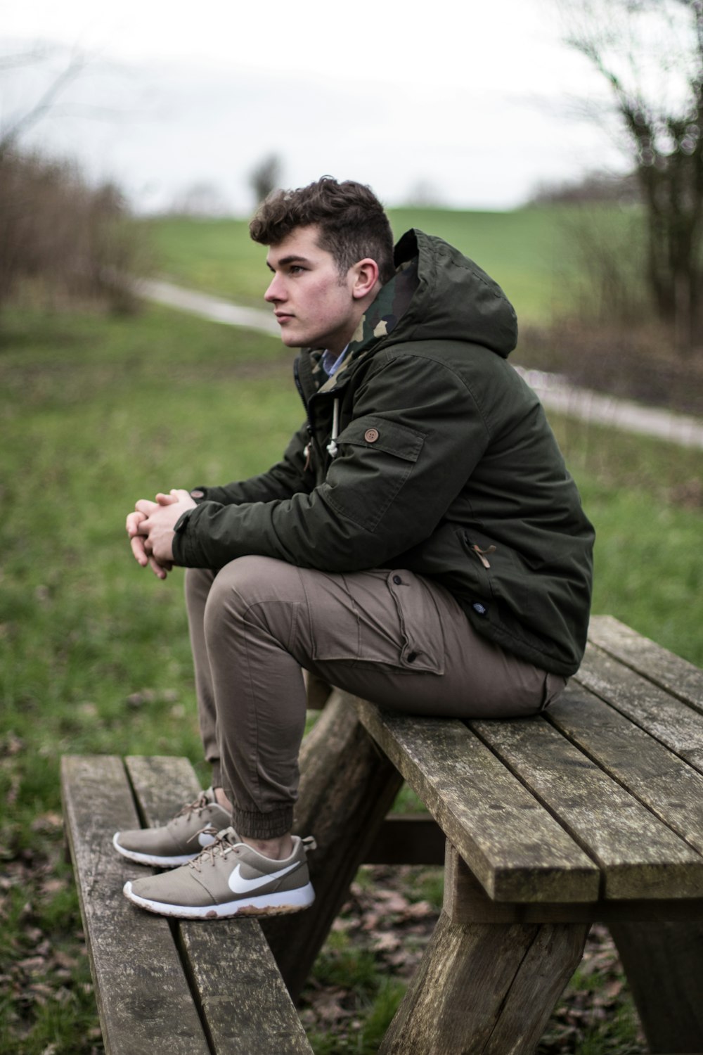 man sitting on brown wooden picnic bench during daytime