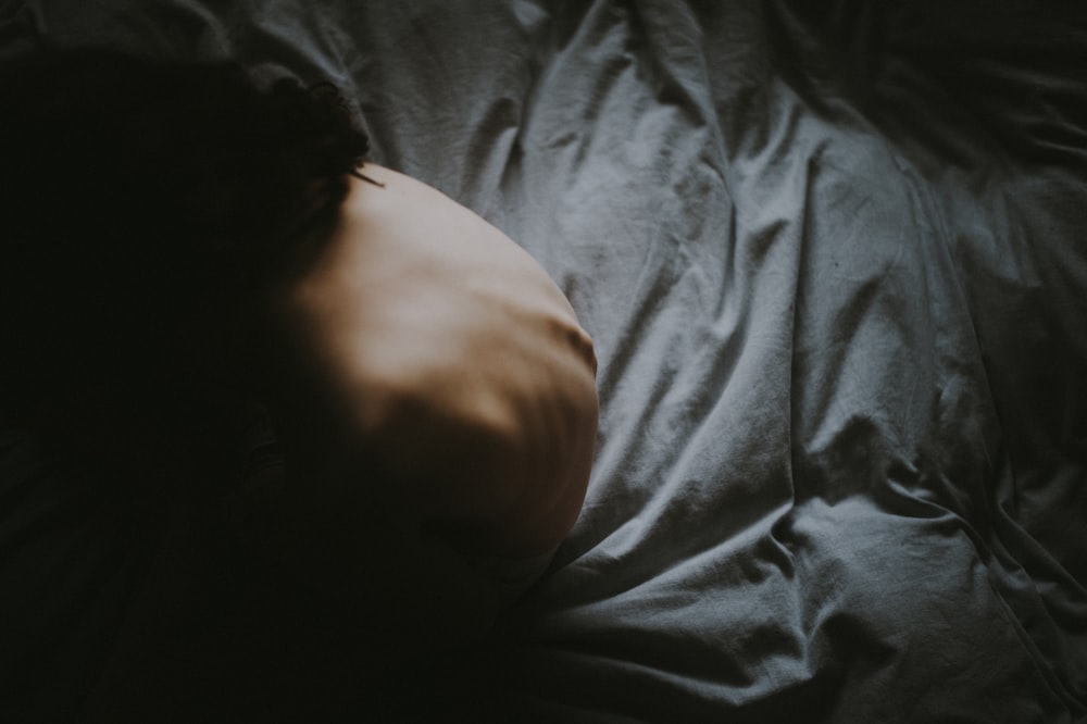 a person sleeping on a bed with a dark background