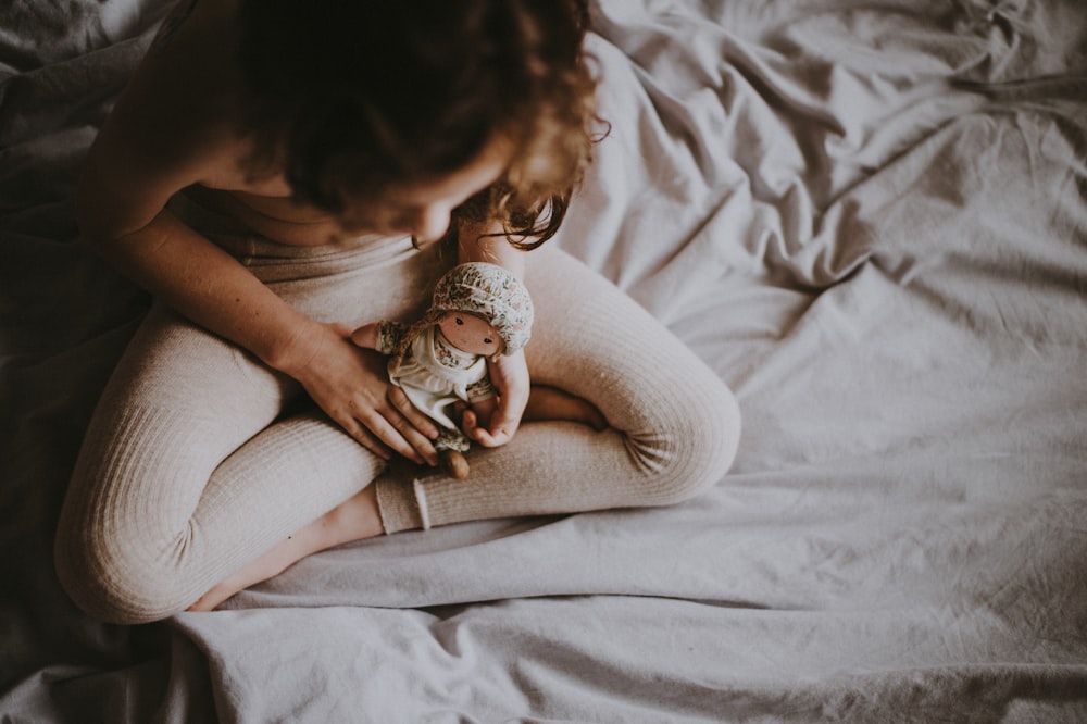 person holding doll on white textile