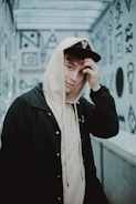 man in hoodie standing near white painted wall