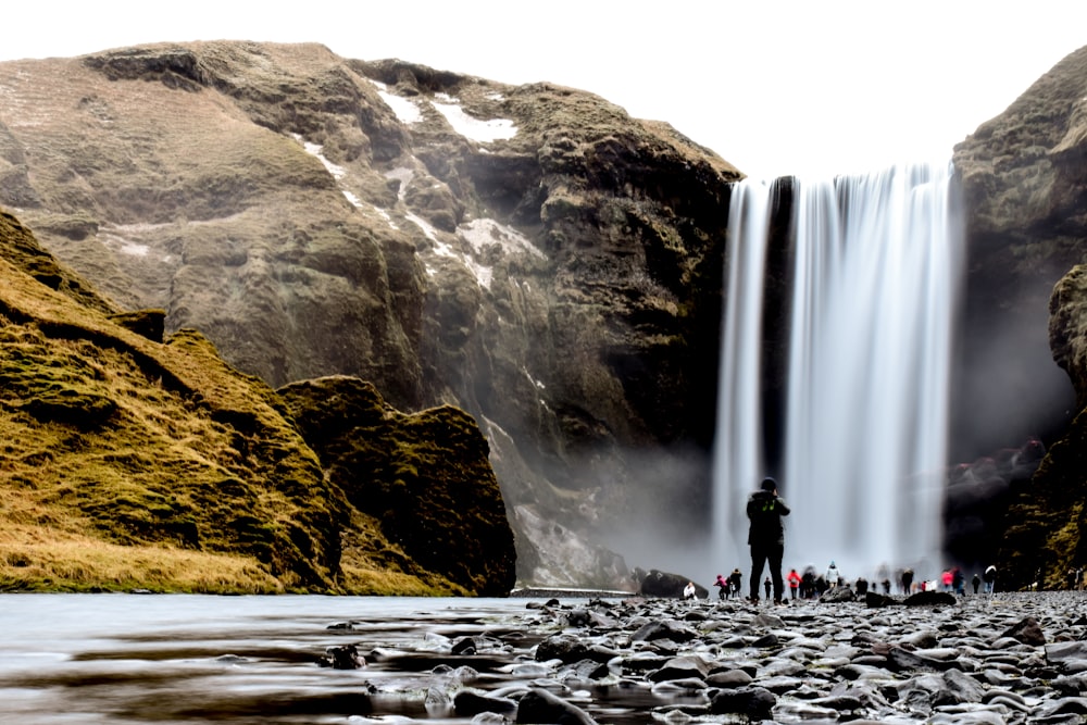 group of people standing near waterfalls