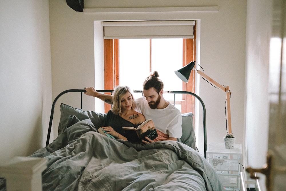 homem e mulher lendo livro na cama