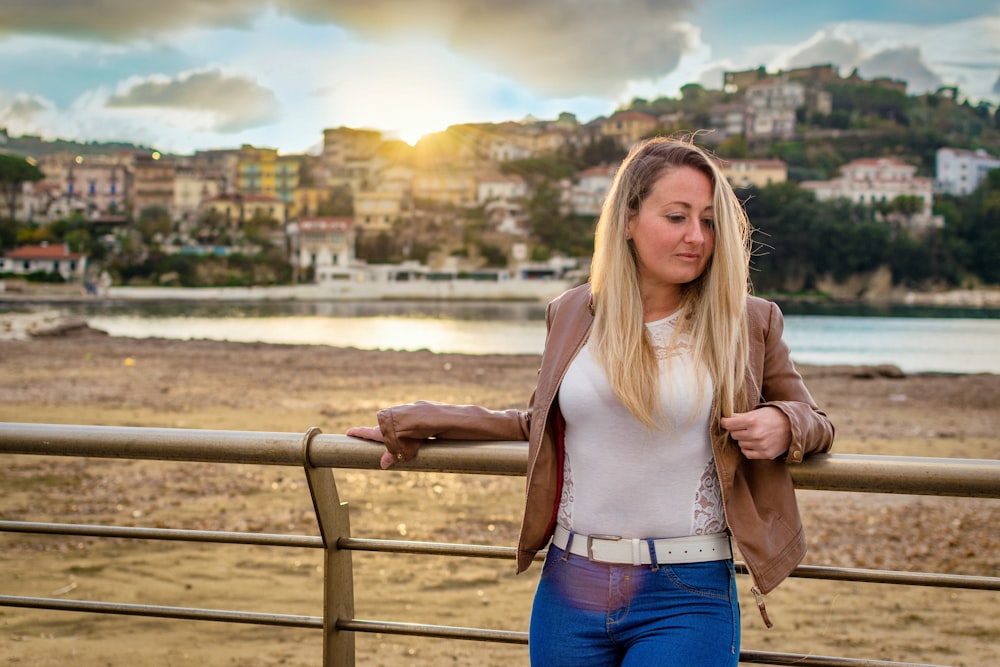 woman leaning on bridge rail in front of buildings