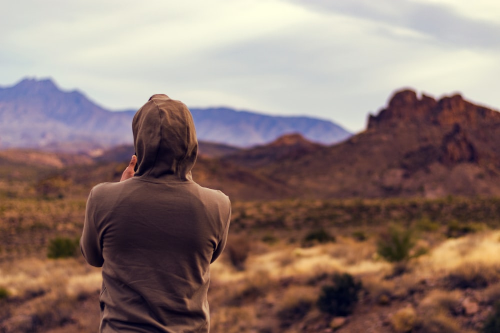 person wearing gray shirt facing jagged cliffs