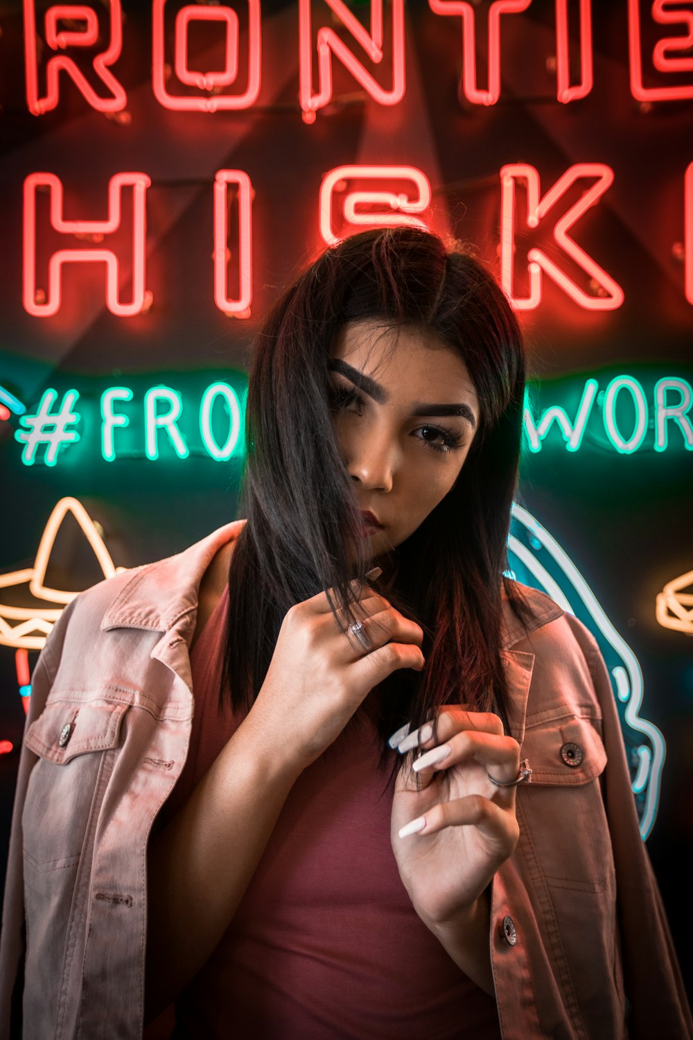 woman wearing red top behind neon light signage