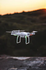 flying quadcopter drone during sunset
