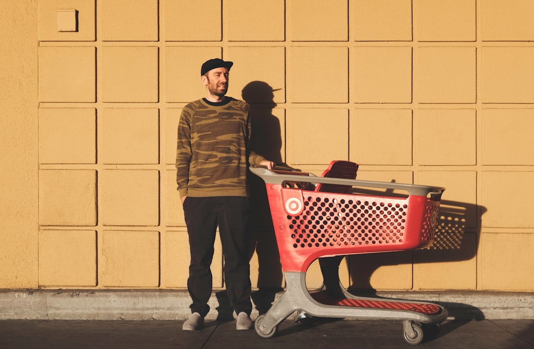 man standing near red and gray shopping cart