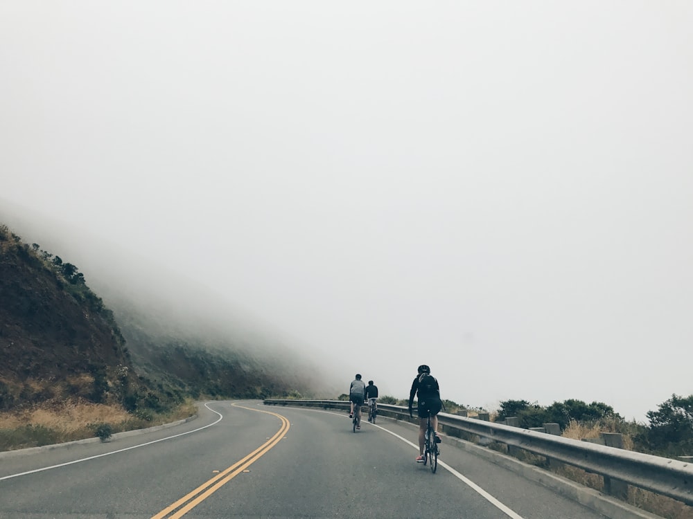 three men biking on asphalt road