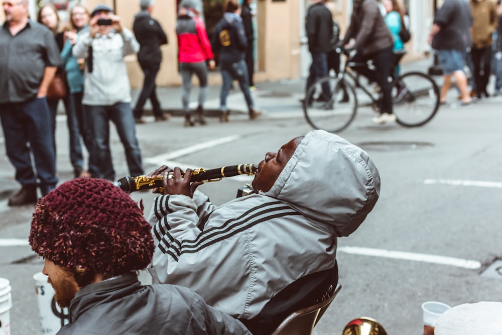 man sitting on chair playing flute