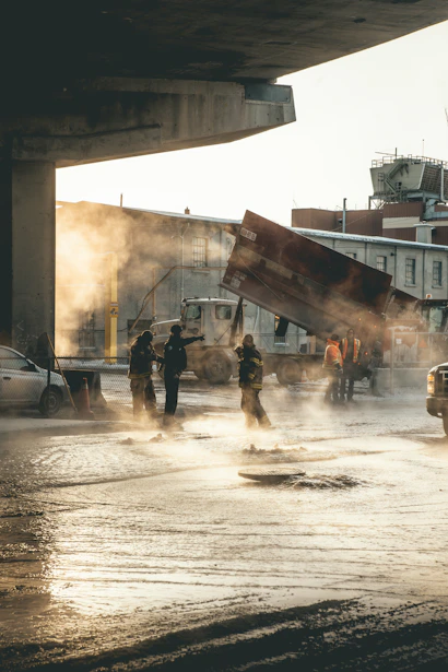 firemen walking on flooded road with cars and trucks