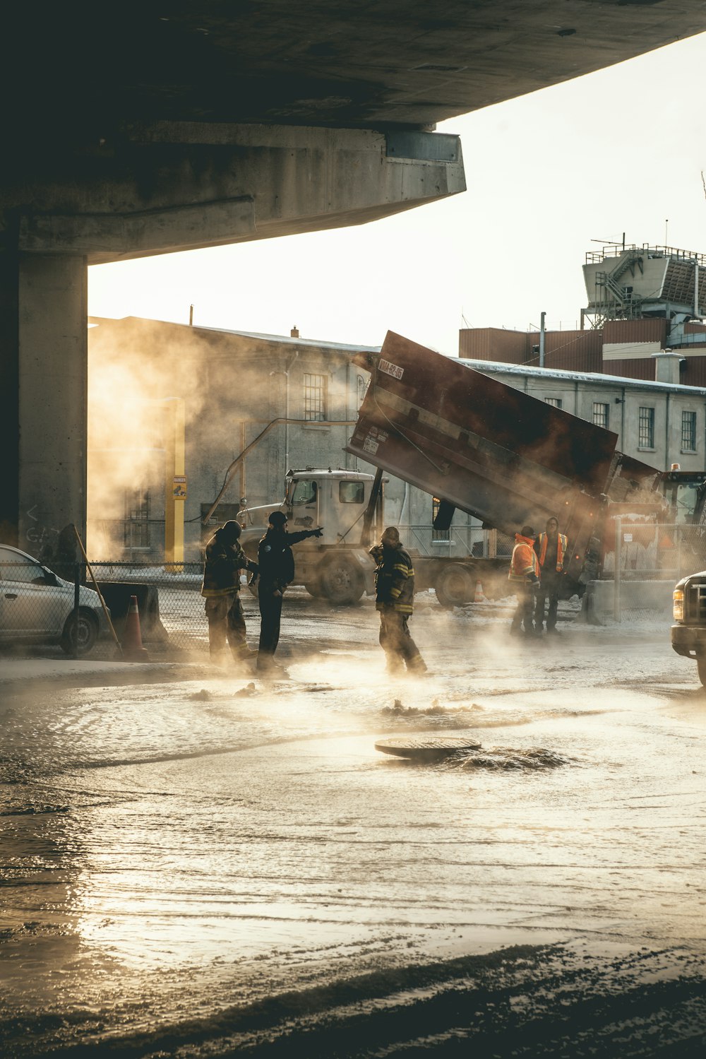 Des pompiers marchant sur une route inondée avec des voitures et des camions