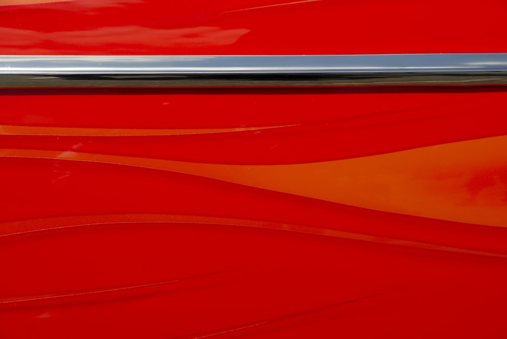 a close up of a red car with a silver stripe