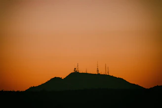 A scenic shot of antennas stretching across a grassy hilltop at sunset.