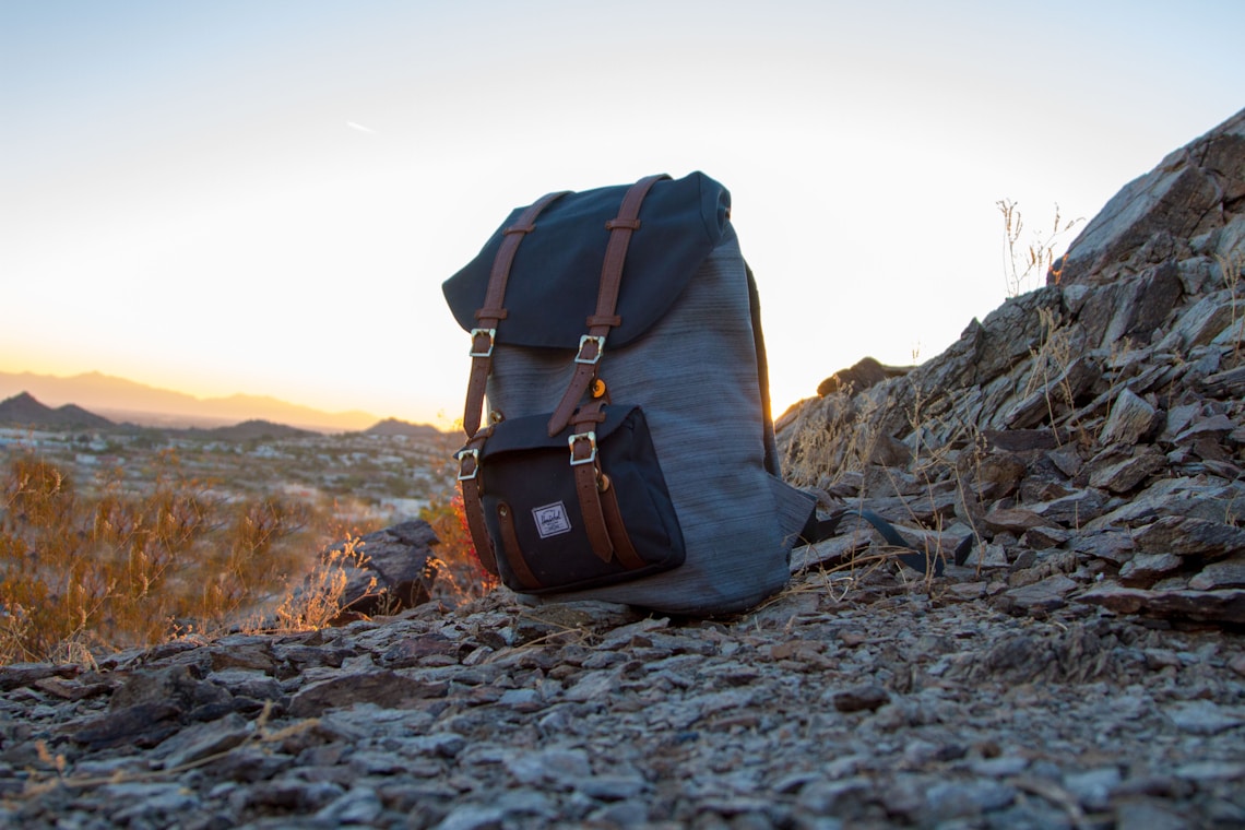 gray and black backpack on top of cliff