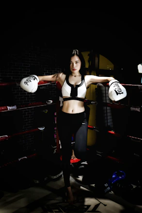A determined fighter lacing up gloves in a vibrant gym filled with punching bags and cheering spectators.