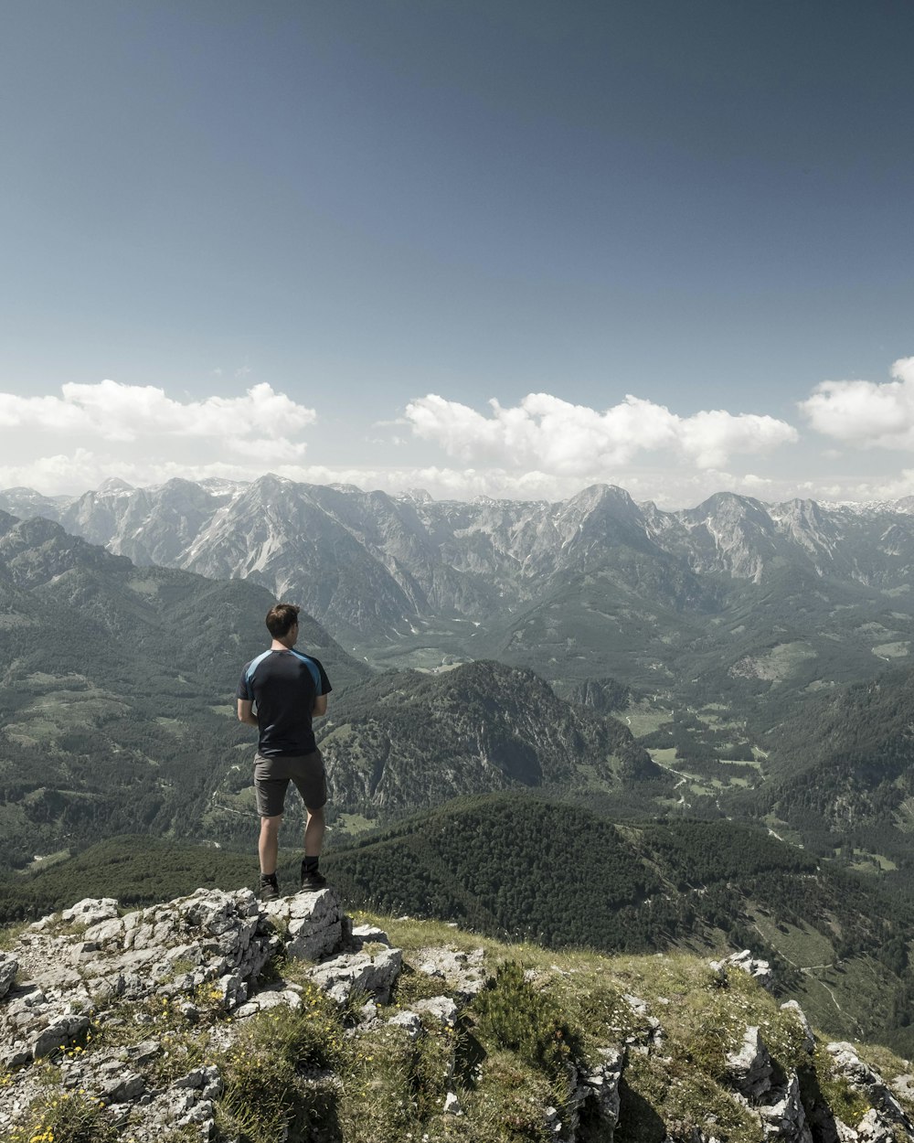 hombre de pie en el acantilado mientras mira fijamente a la montaña