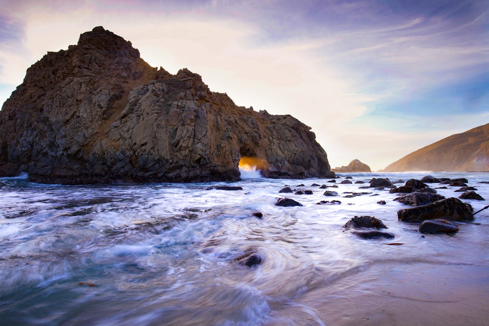 time lapse photography of body of water near rock formation