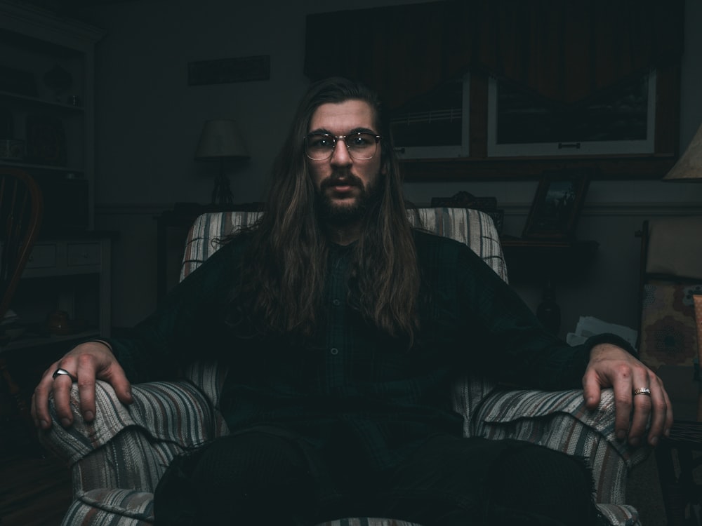 man in black dress shirt sitting on sofa chair