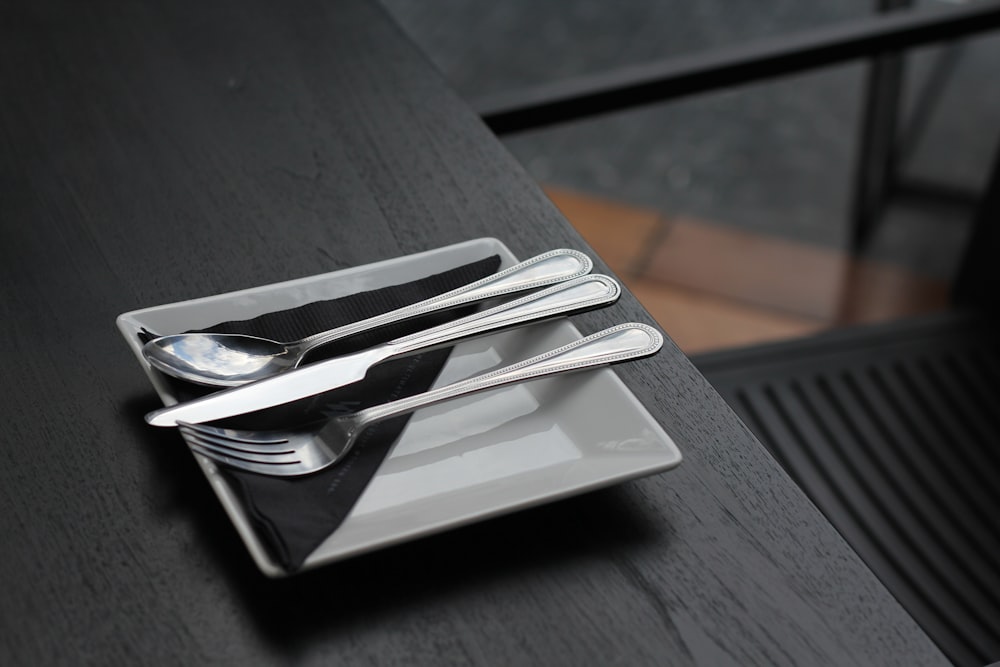 stainless steel spoon and fork on black ceramic plate