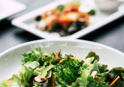 Close-up of a colorful salad bowl with fresh greens, cherry tomatoes, and nuts.