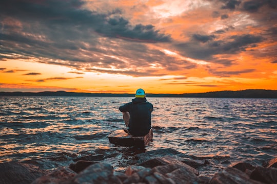 man sitting on gray rock during sunset in Årjäng Sweden