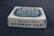 A white rectangular box sits on a dark surface. The front of the box is labeled with the text 'Stainless Steel STIRRUP CUP' in a bold, dark font. The top of the box also contains text, but it is partially obscured, with 'One for the Road' and 'Stainless Steel' visible.
