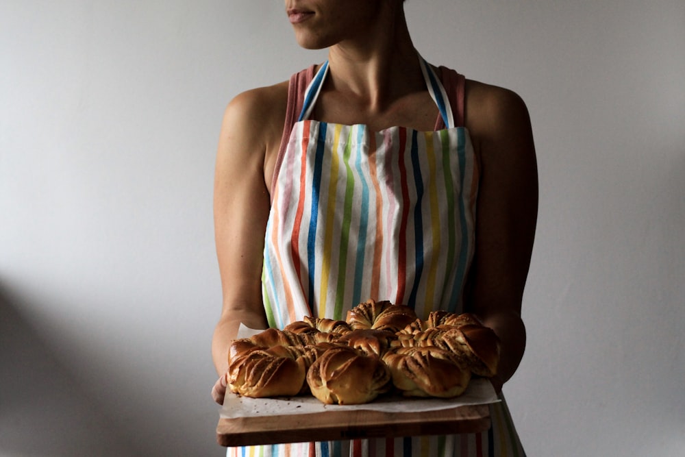 mulher segurando bandeja com pães