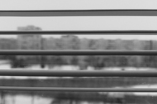 Modern charcoal-colored blinds partially open in a stylish office overlooking the city.