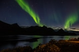 Mesmerizing northern lights dancing over a serene Icelandic fjord at twilight