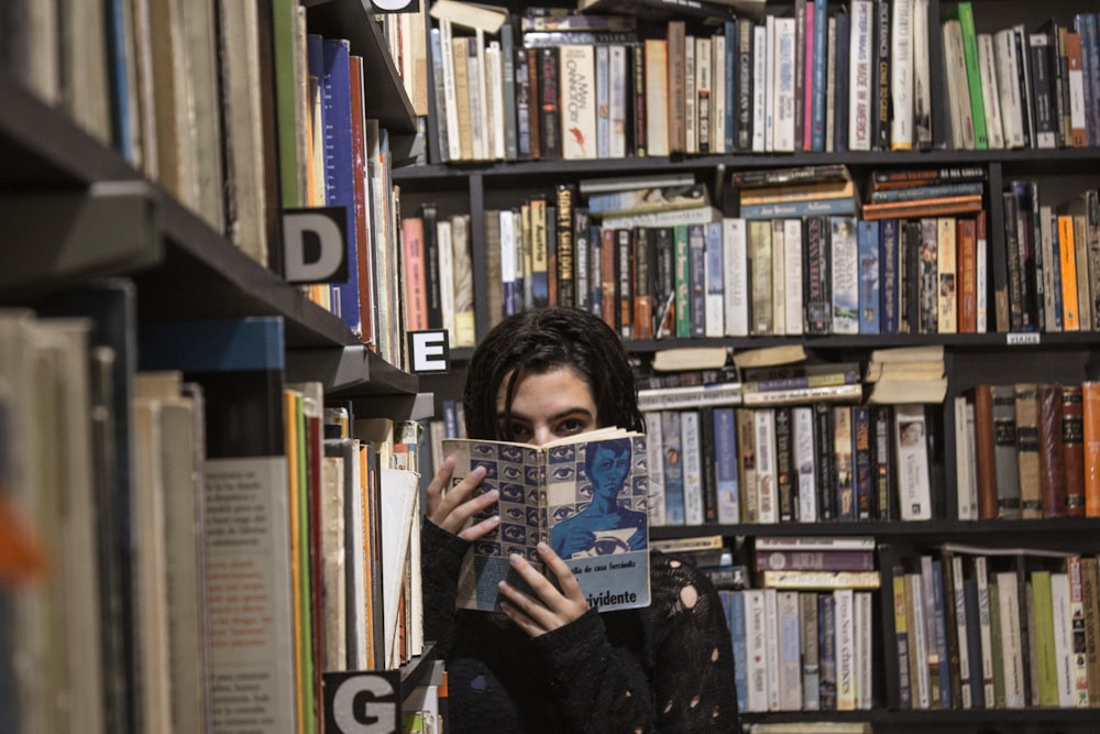 woman holding book covering half face