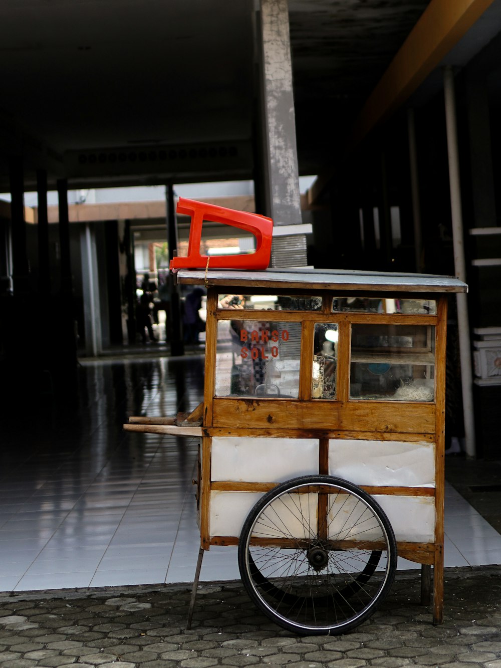 Tabouret en plastique rouge sur chariot de magasin en bois brun et blanc