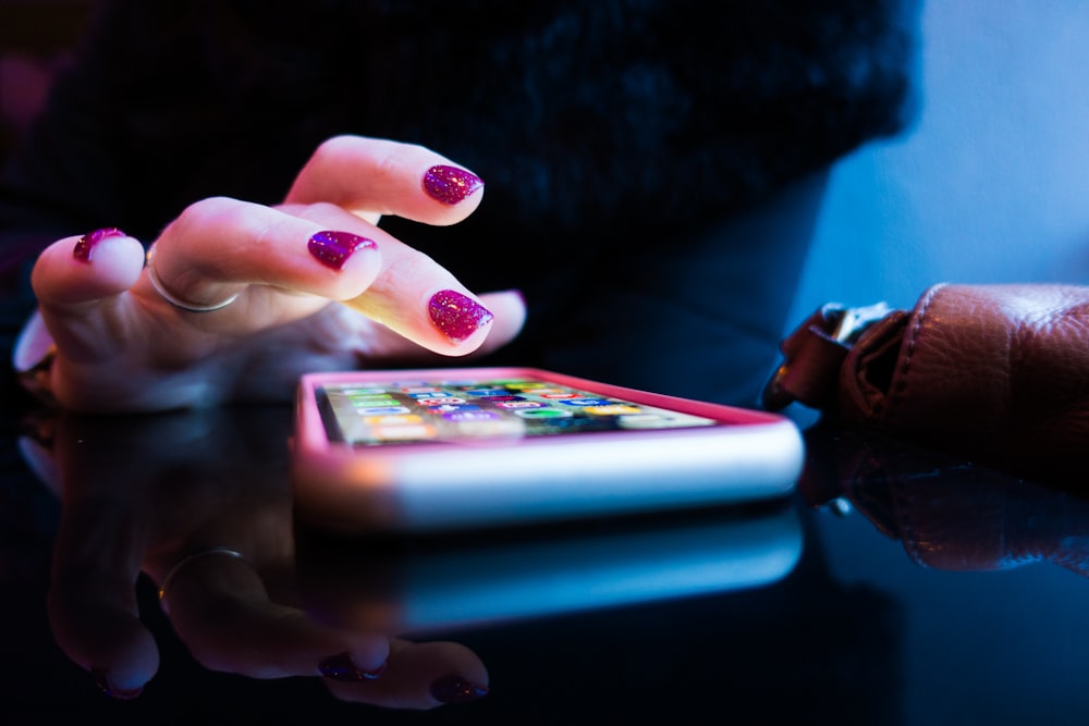 Persona usando teléfono inteligente negro con funda gris y rosa