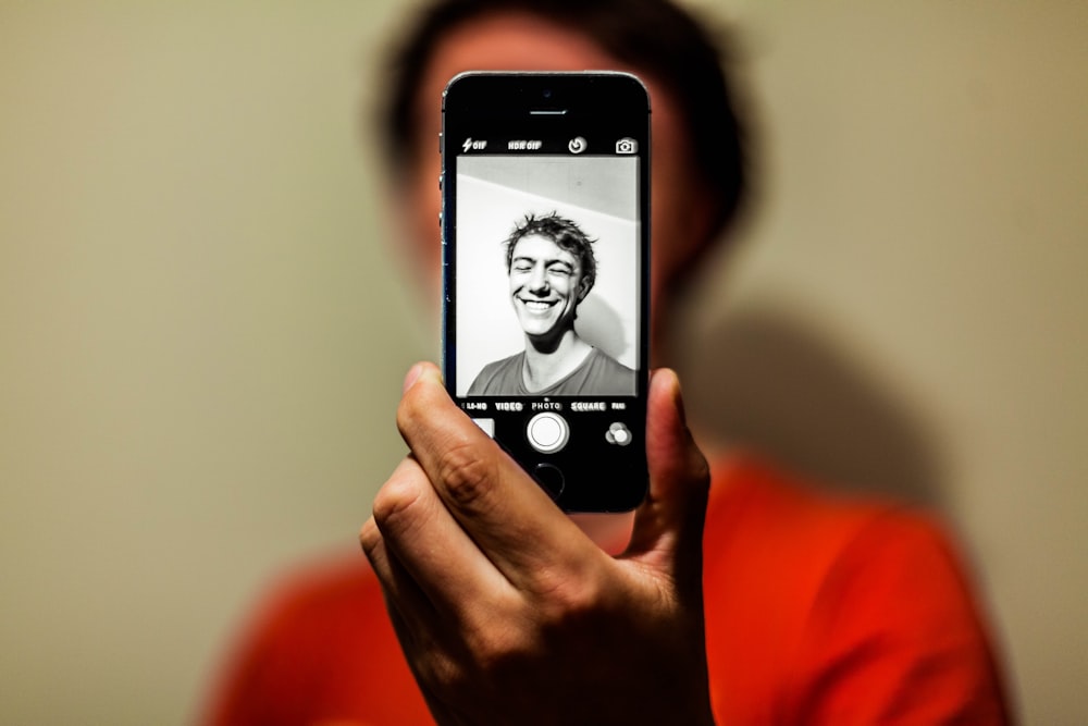 persona sosteniendo el espacio gris iPhone 5s tomando una foto