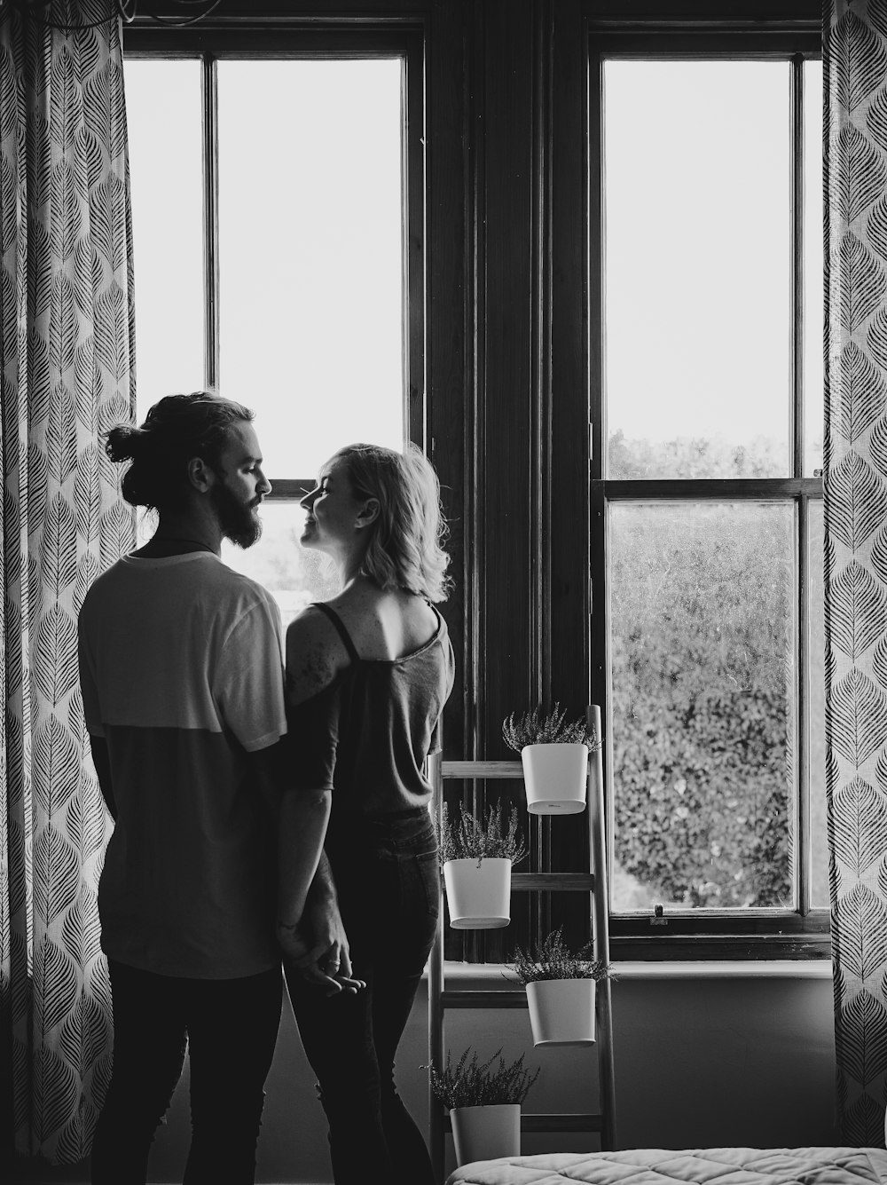 man and woman facing each other near window