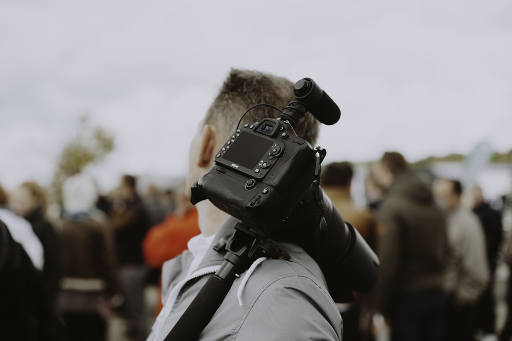 homme avec un appareil photo reflex numérique noir sur son épaule
